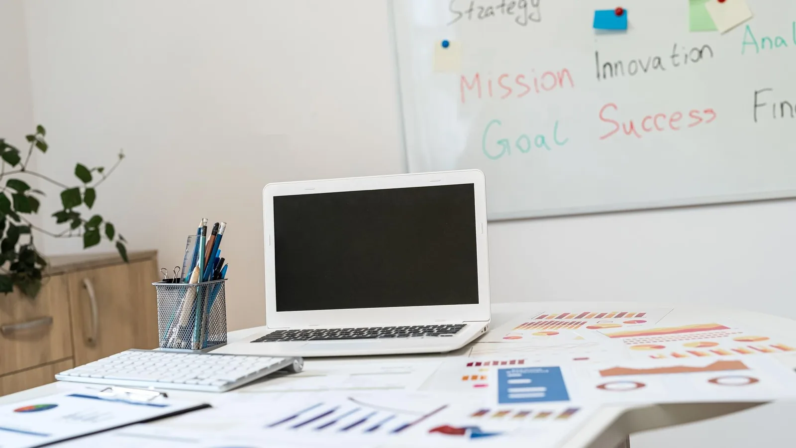 Pianificazione della strategia di marketing per piccola impresa su lavagna Scrivania con laptop, grafici e lavagna di pianificazione della strategia di marketing per una piccola impresa